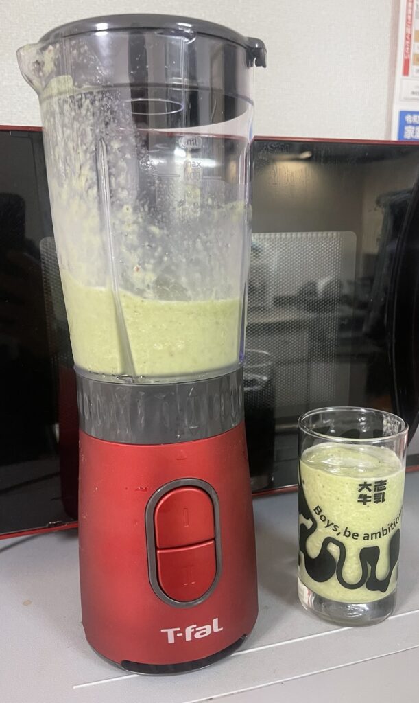 Finished komatsuna and apple milk smoothie in a glass, creamy green drink made with milk, apple, and leafy greens