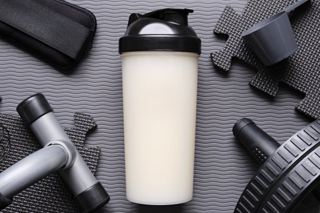 ヨガマット上の牛乳プロテインと筋トレグッズのイメージ