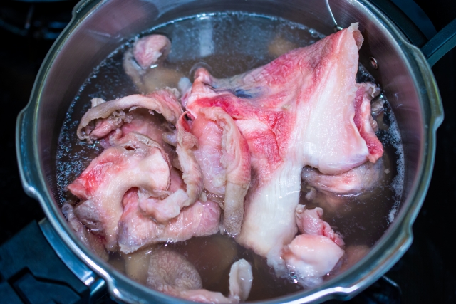 牛すじの下処理手順を示す湯通しとアク取りの調理画像