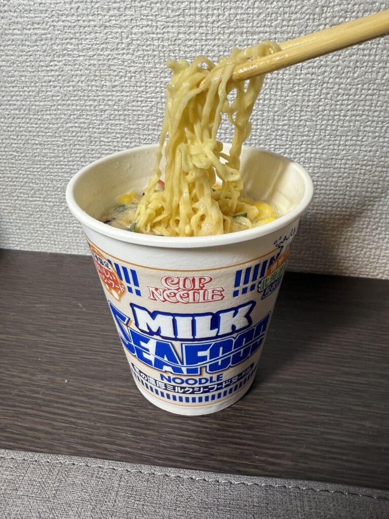 カップヌードル冬の濃厚ミルクシーフードヌードルを箸で持ち上げた写真