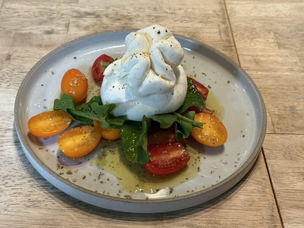 たっぷりトマトとブッラータチーズにオレガノを添えた写真