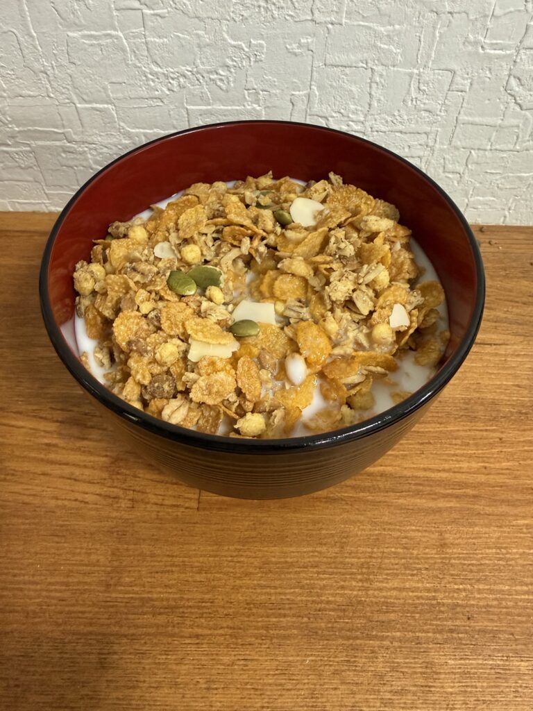 素材まるごとグラノラ パリッとアーモンド やさしいはちみつ味に牛乳をかけた朝食イメージ